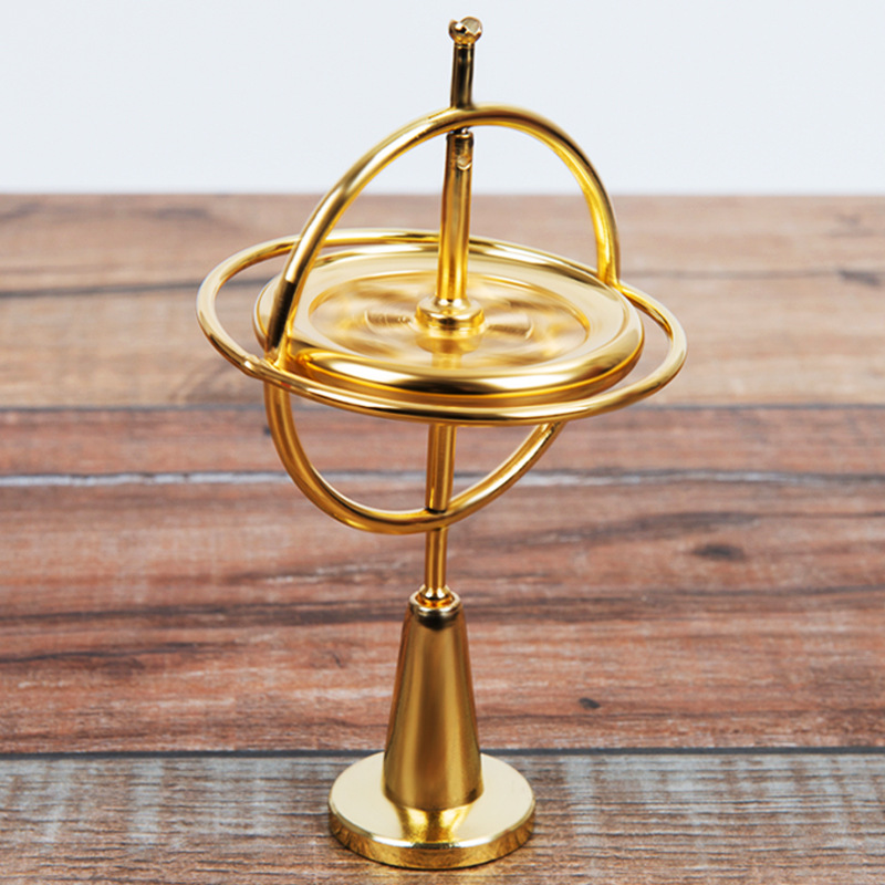 Orbitrix gyroscope in gold finish, front view on wood surface