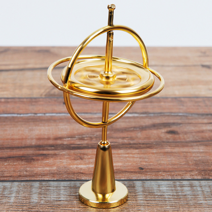 Orbitrix gyroscope in gold finish, front view on wood surface