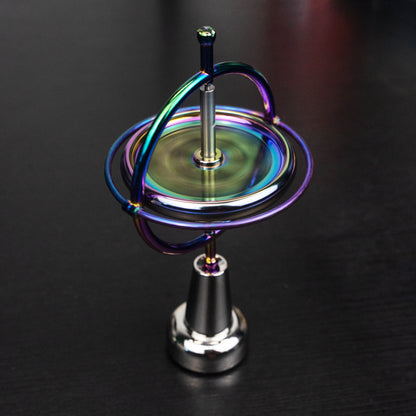Orbitrix gyroscope in iridescent rainbow finish, spinning on its stand